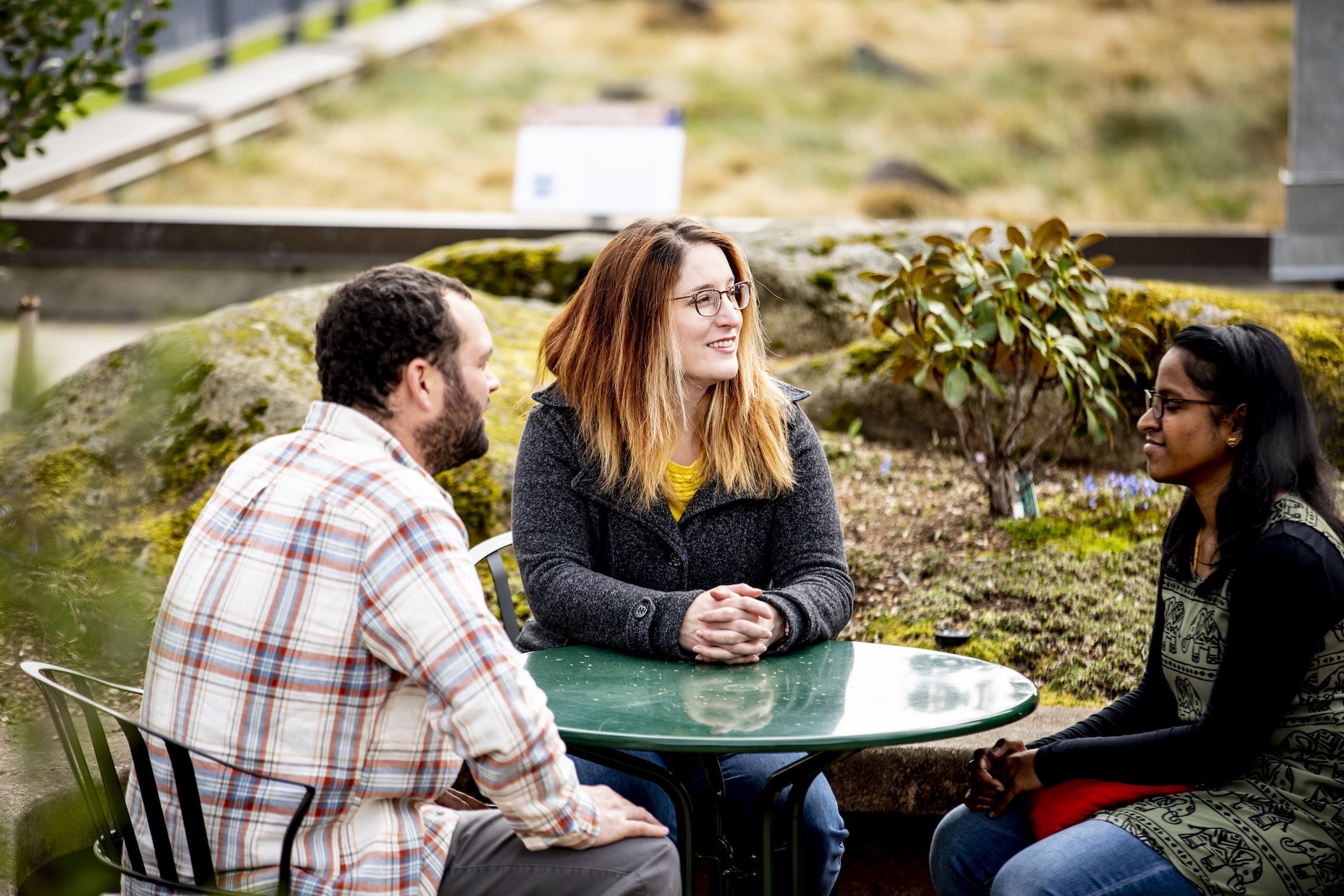 Three people seated at an outdoor table.