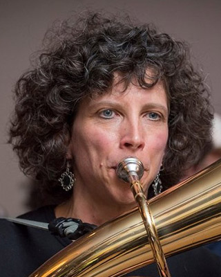 Whitney looks ahead while playing a brass instrument.