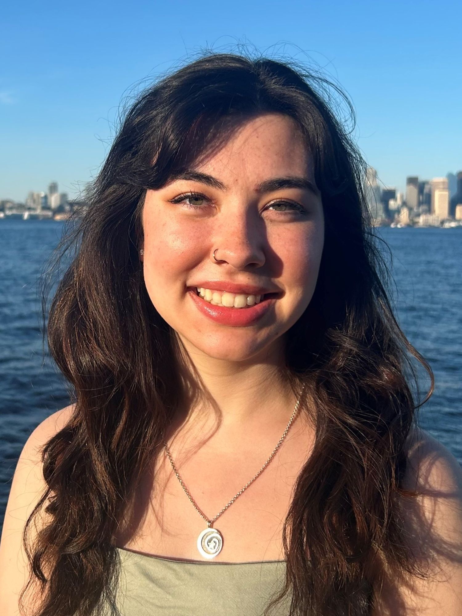 Ellis smiles at the camera standing in front of a body of water.