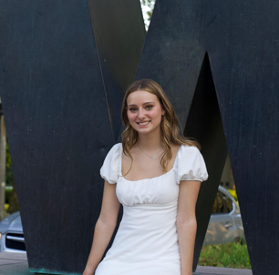 Annabelle smiles at the camera wearing a white dress.