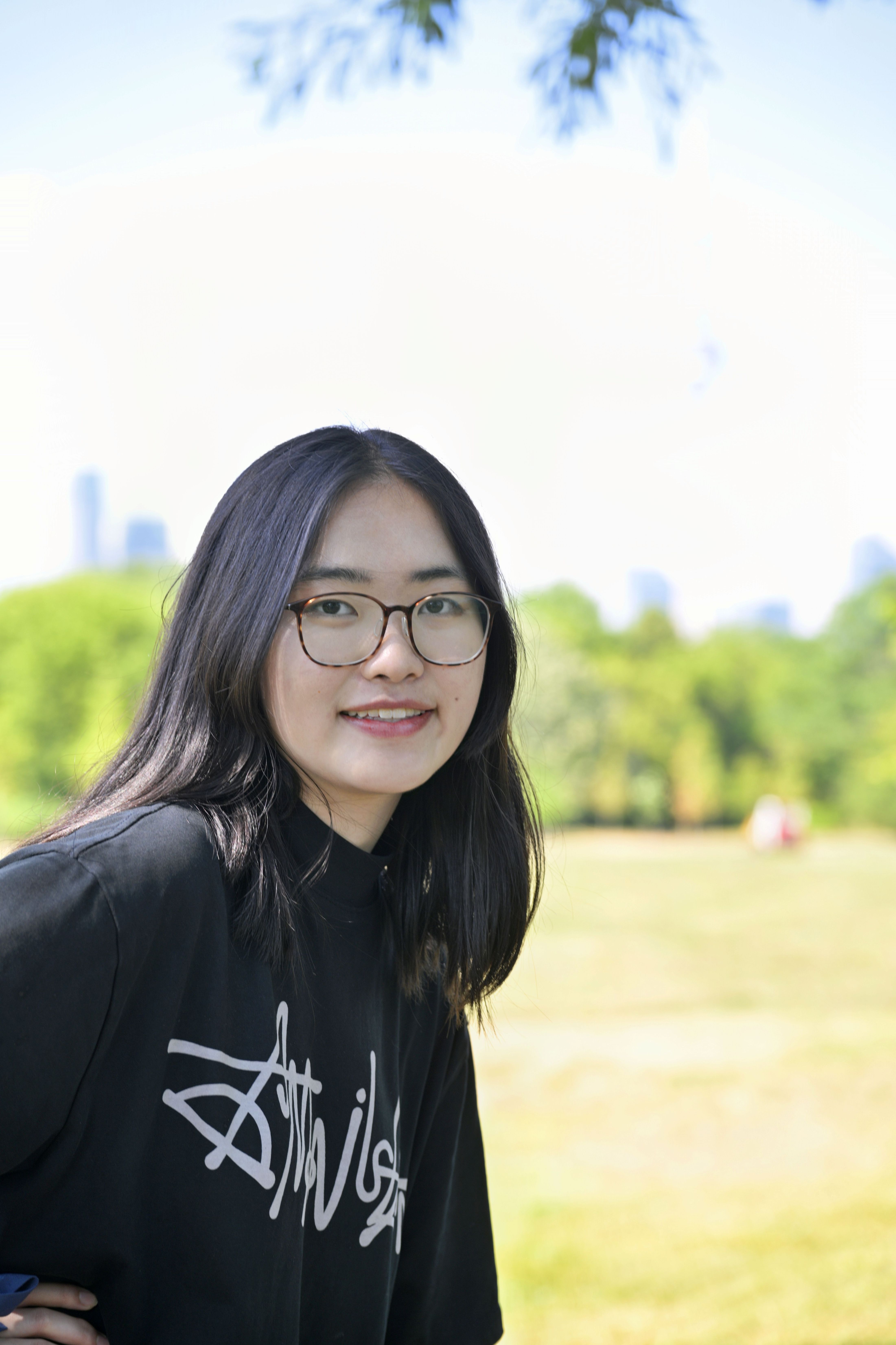 Jingyun smiles at the camera wearing a black shirt and glasses.